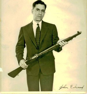 John Garand holding his rifle design, the M1, commonly known as the 'M1 Garand'.